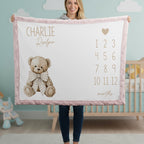 Woman holding personalized teddy bear milestone minky blanket with pink trim in cloud nursery