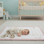 Baby sleeping on personalized teddy bear milestone minky blanket with pink trim on nursery floor