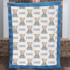 Personalized teddy bear minky baby blanket with blue fur border held up by brick fireplace