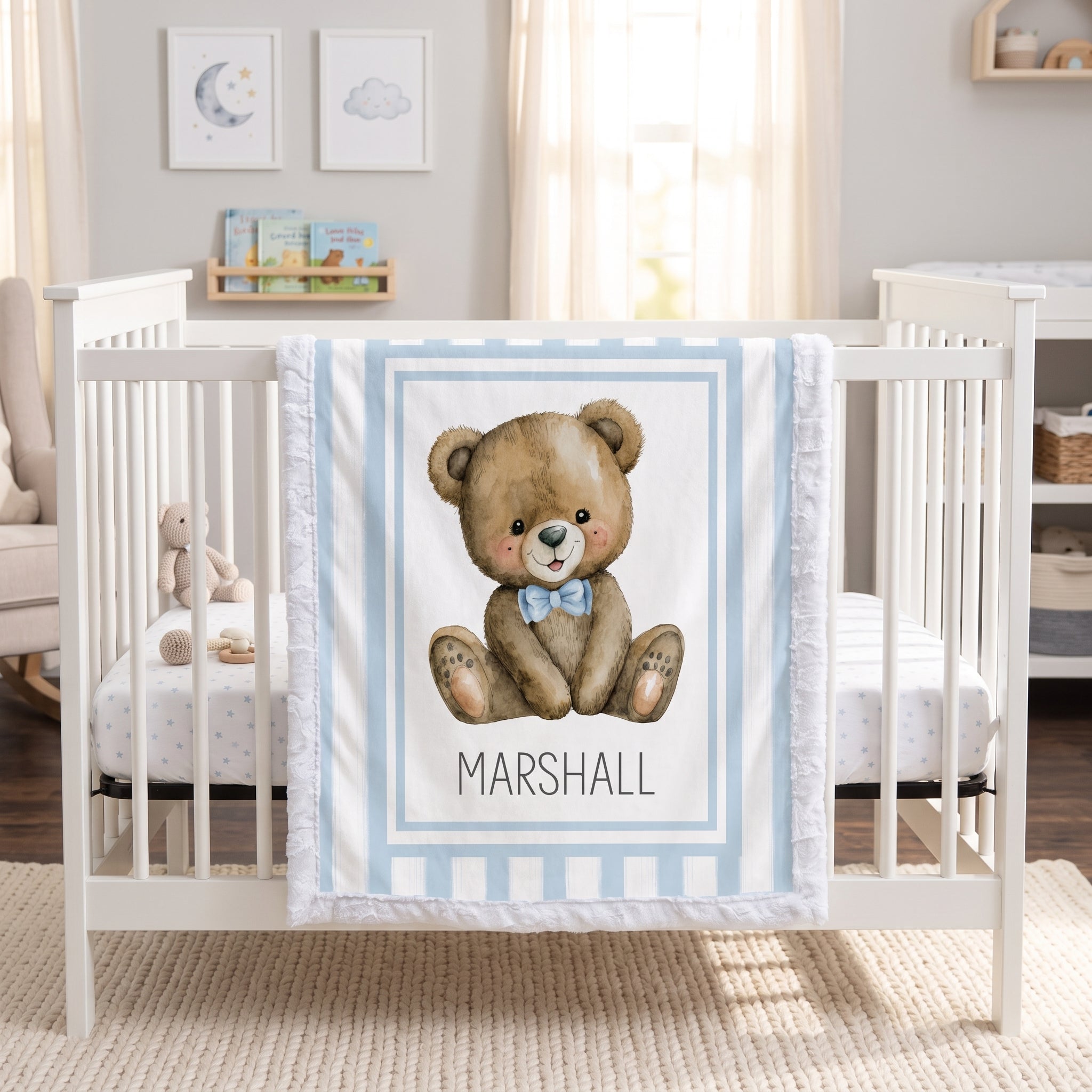 Personalized minky teddy bear baby blanket with blue stripe border draped over white crib