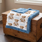 Personalized minky baby blanket with teddy bear print draped over wooden chest near window