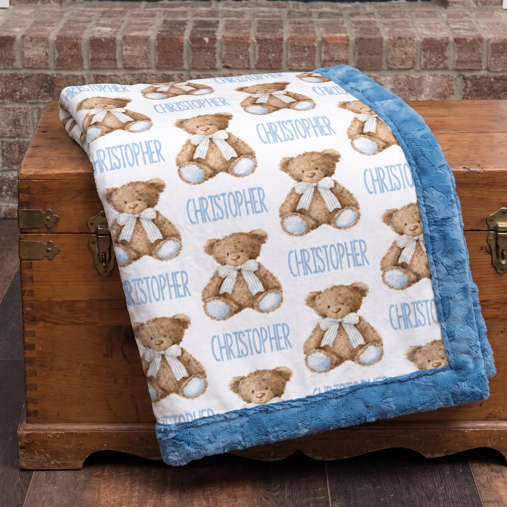 Personalized teddy bear minky baby blanket folded on a wooden trunk by a brick fireplace