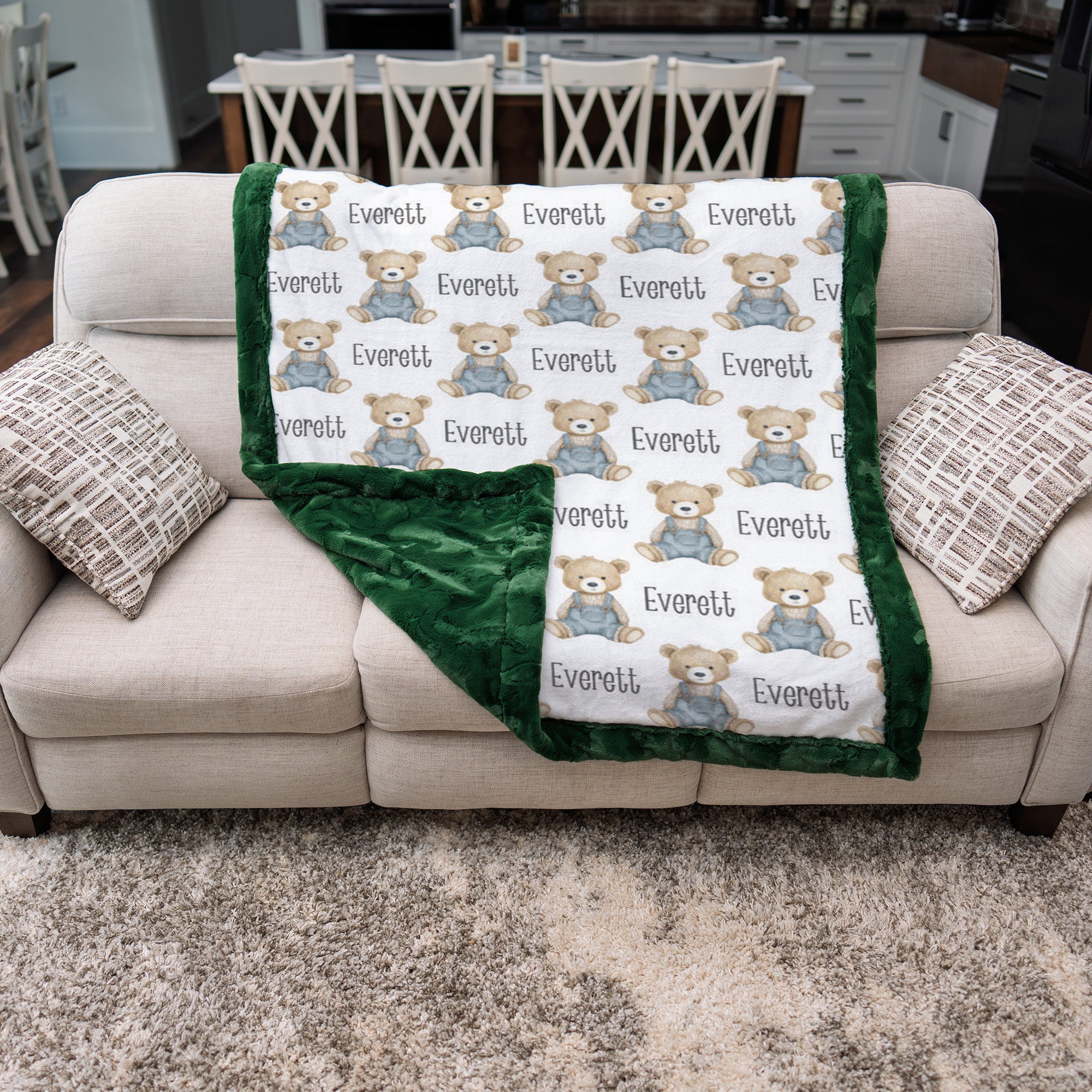 Personalized teddy bear minky baby blanket with green fur border draped over couch, minky back showing