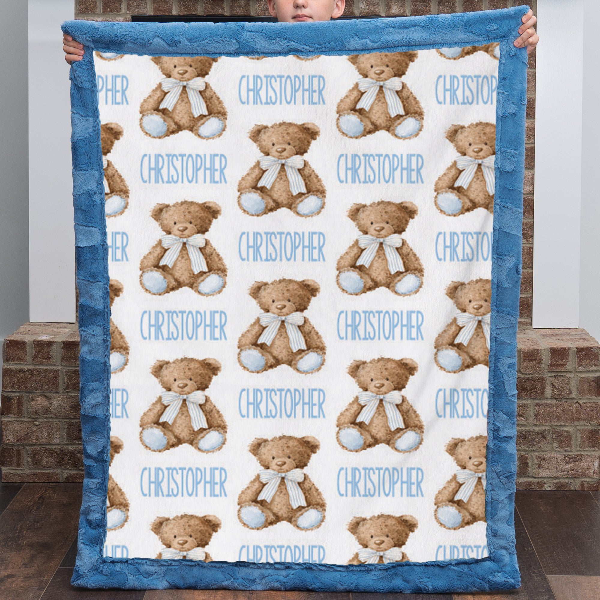 Personalized teddy bear minky baby blanket held up by a child, name printed throughout the pattern