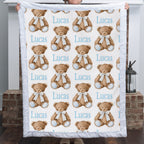 Personalized minky baby blanket with teddy bear print held up to show full pattern by fireplace