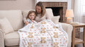 Mother and toddler holding personalized teddy bear minky baby blanket with Isabella name on couch
