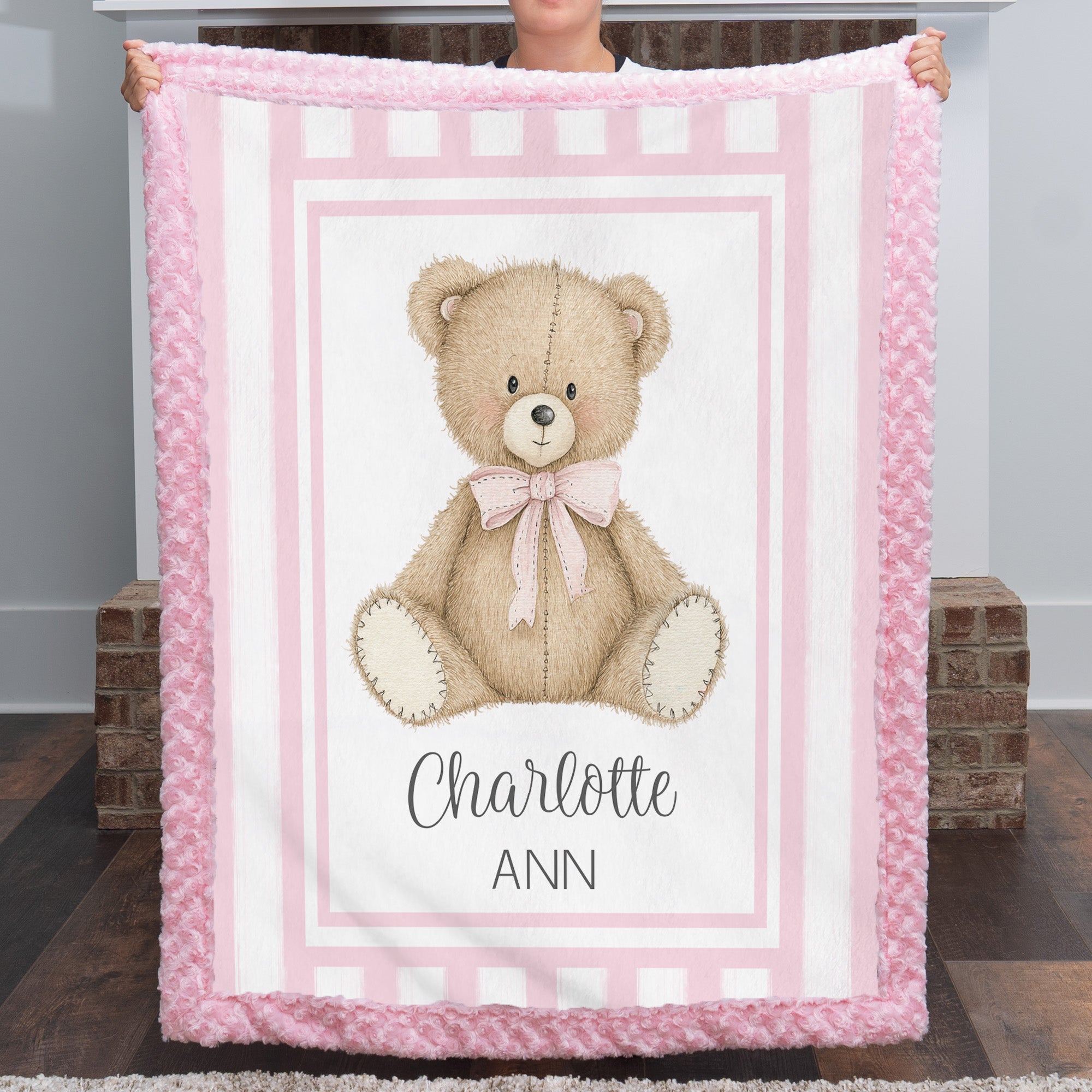 Personalized minky teddy bear baby blanket with pink rosette fur border by fireplace mantel