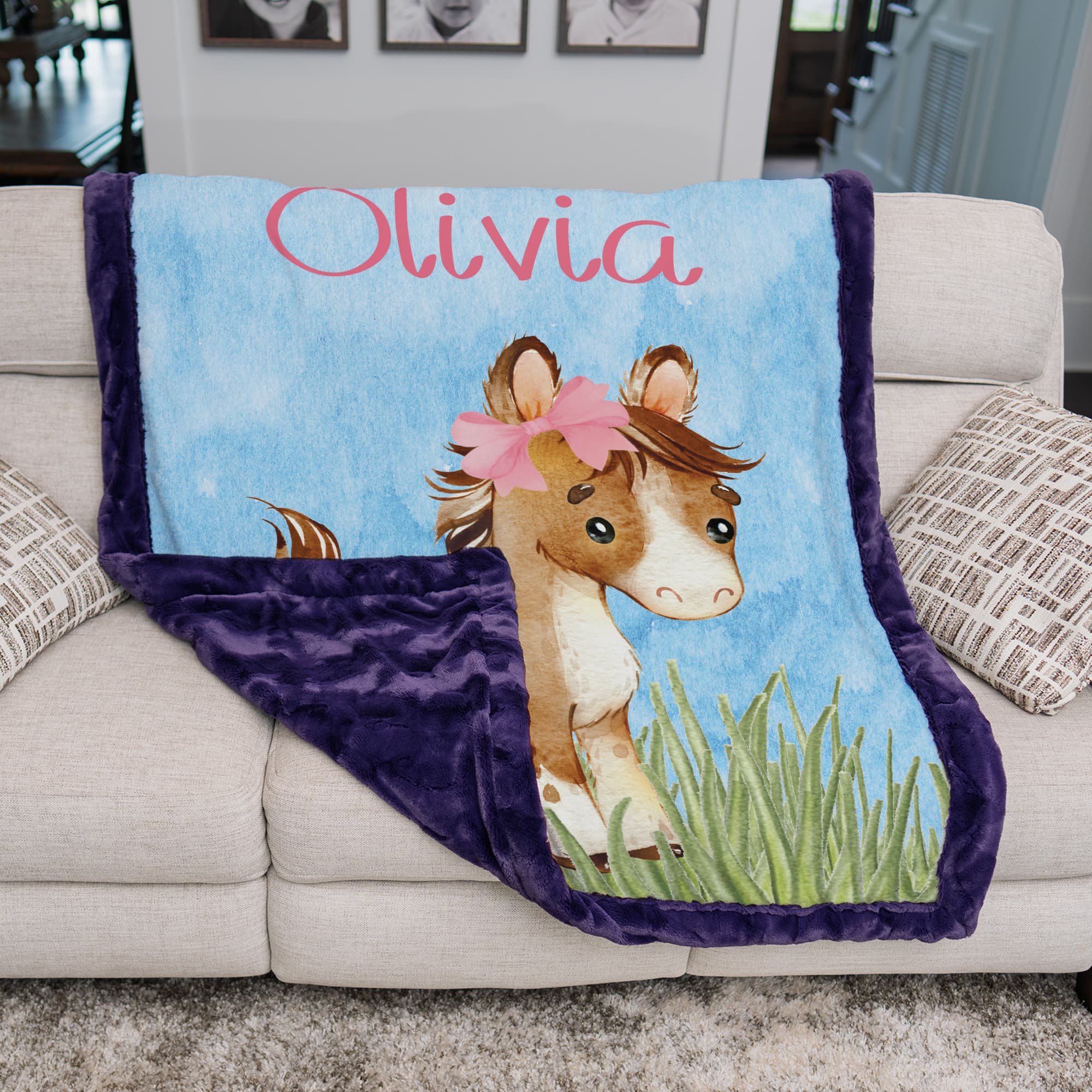 Personalized western pony baby blanket with custom name on cream sofa, purple minky backing shown