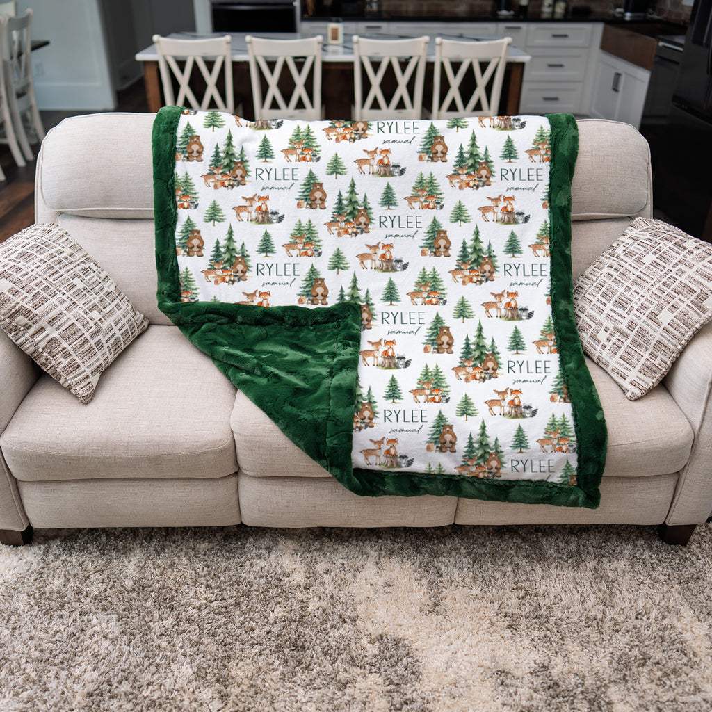 Personalized woodland animal minky blanket with green trim draped over couch