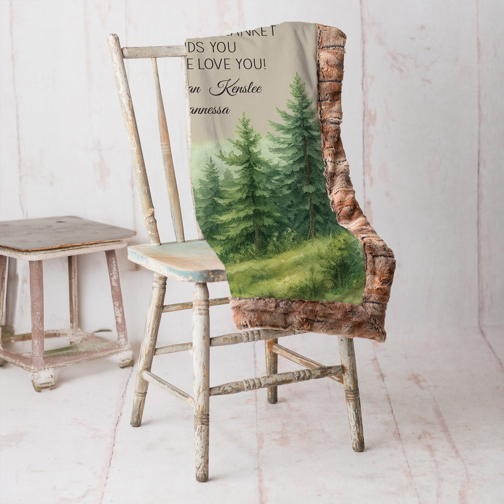 Personalized woodland minky throw draped over rustic chair, watercolor pine forest print and children's names