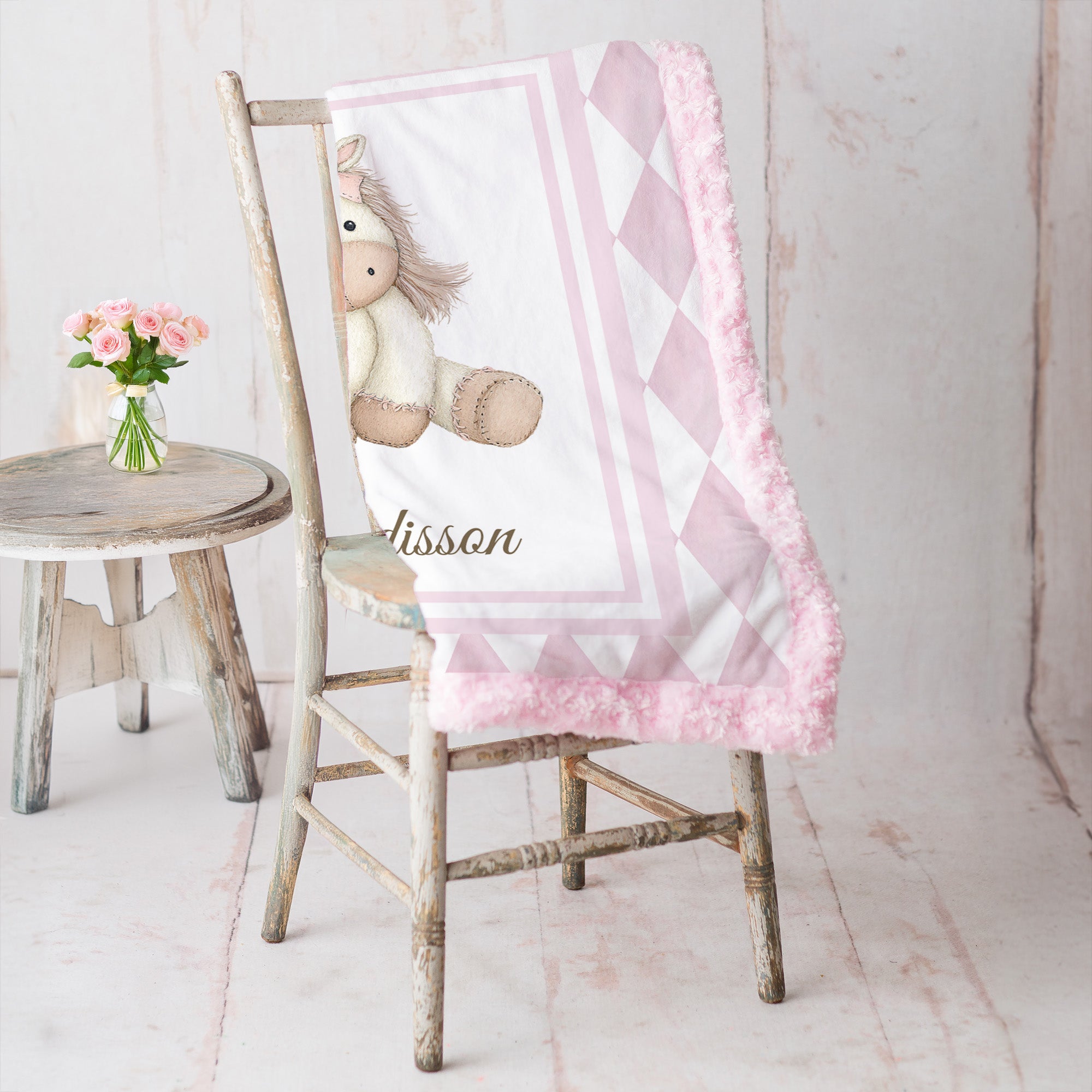 Pink pony minky baby blanket draped over rustic chair, rosette fur backing visible