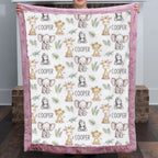 A person holds up a plush minky blanket featuring a repeating pattern of cute safari animals (giraffes, elephants, monkeys, and toddlers) with the name 'COOPER' printed in black text, finished with a dusty pink border.