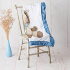 Pony baby blanket with blue minky trim draped over vintage rustic chair