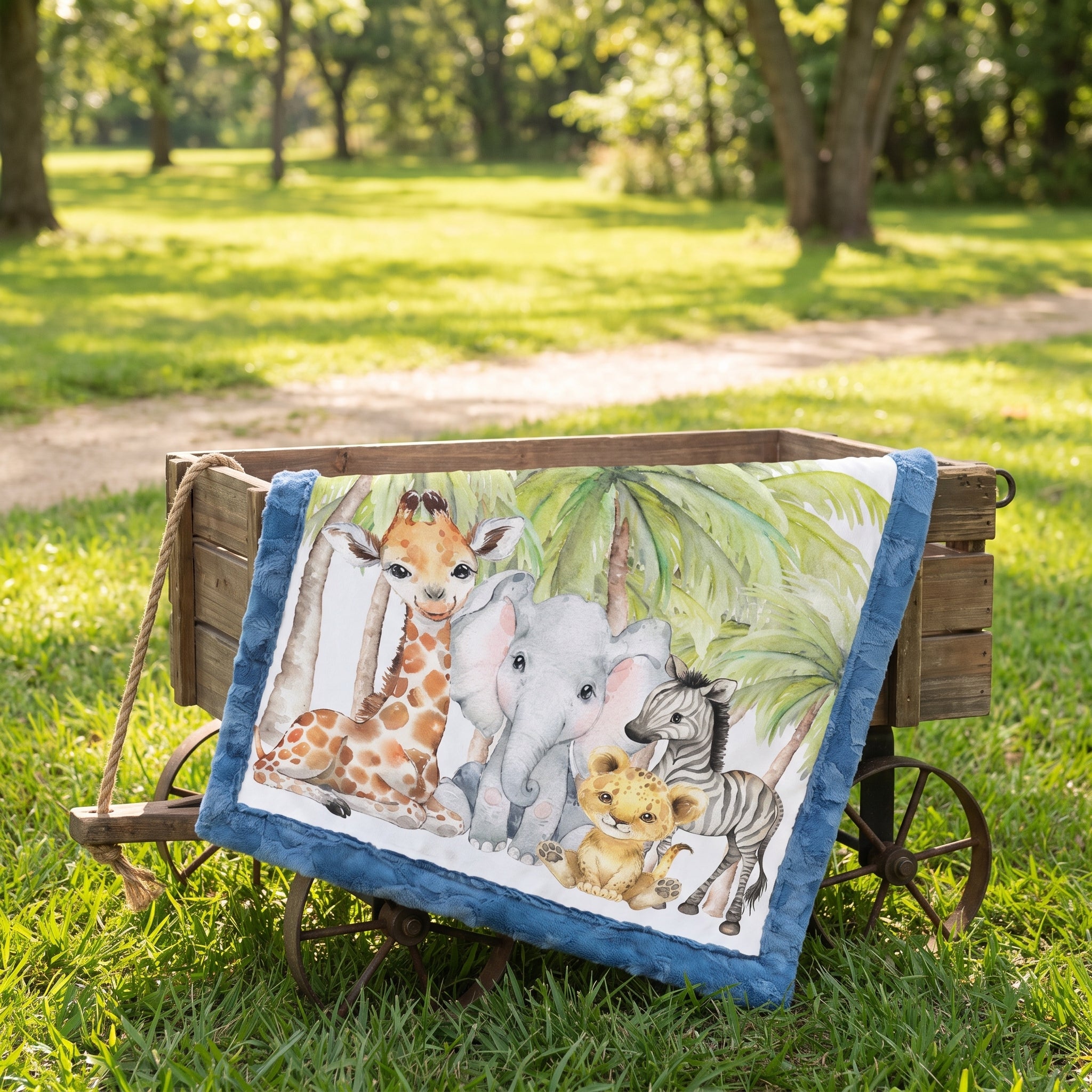 Personalized safari baby blanket draped over wooden wagon in grassy outdoor setting