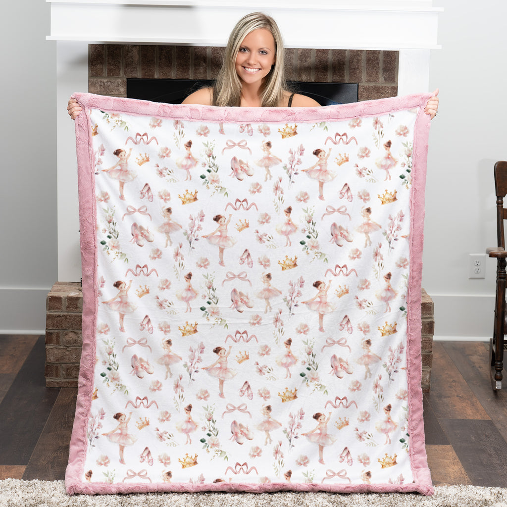 Woman holding a quilt with ballerina pattern in a room.