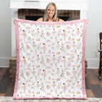 Woman holding a quilt with ballerina pattern in a room.