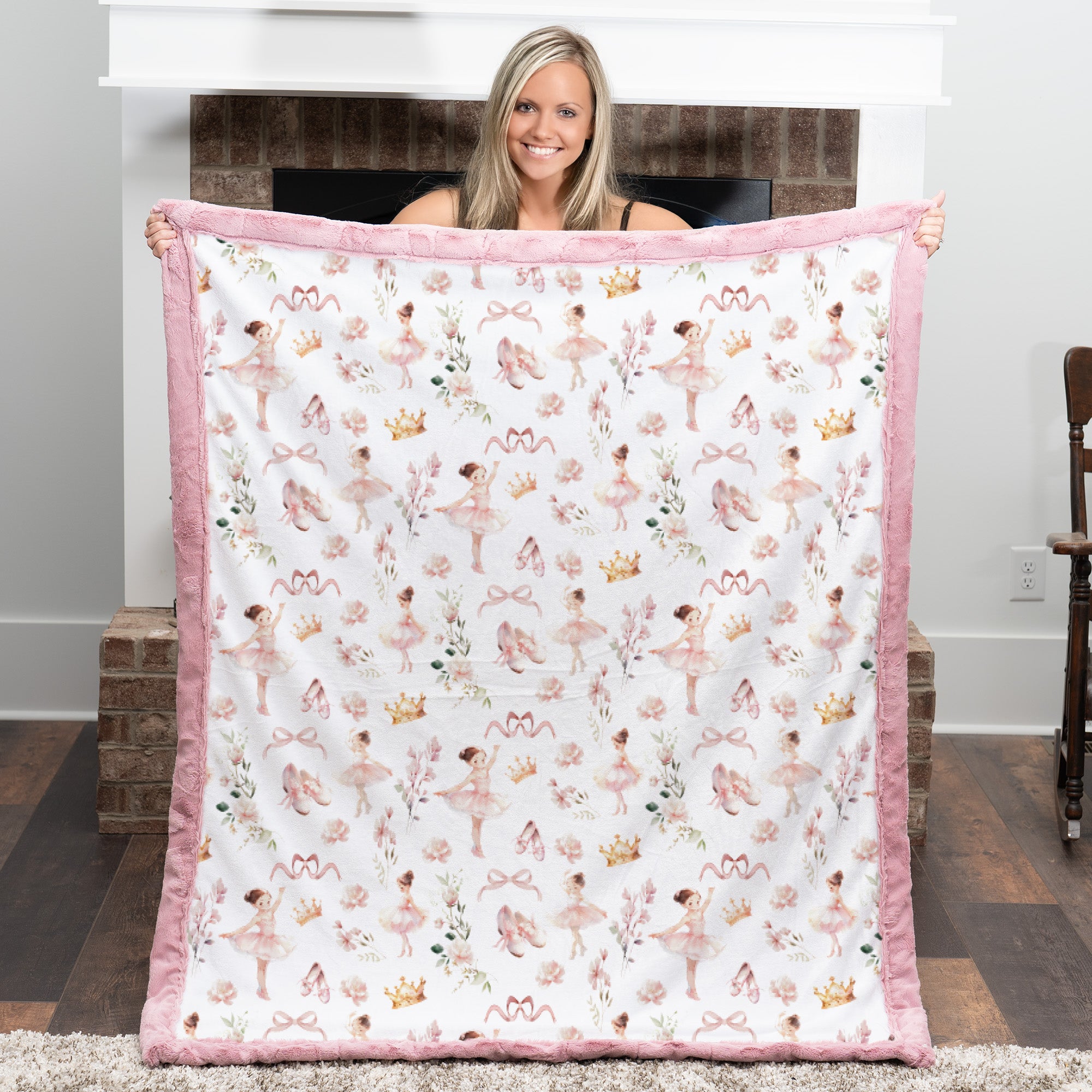 Woman holding a quilt with ballerina pattern in a room.