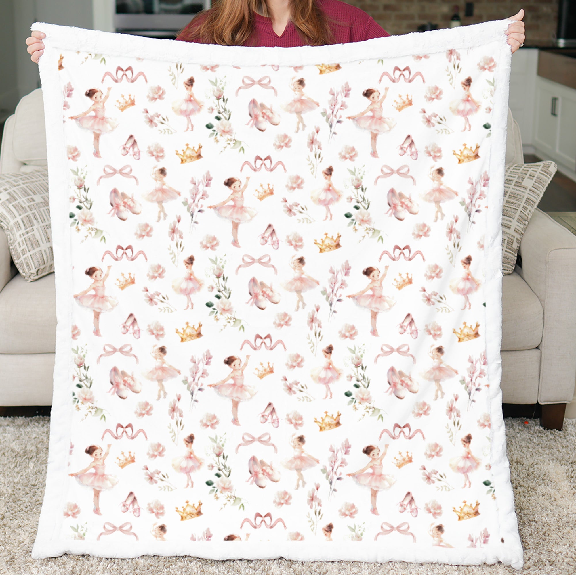 Person holding a blanket with ballerina pattern in a living room setting