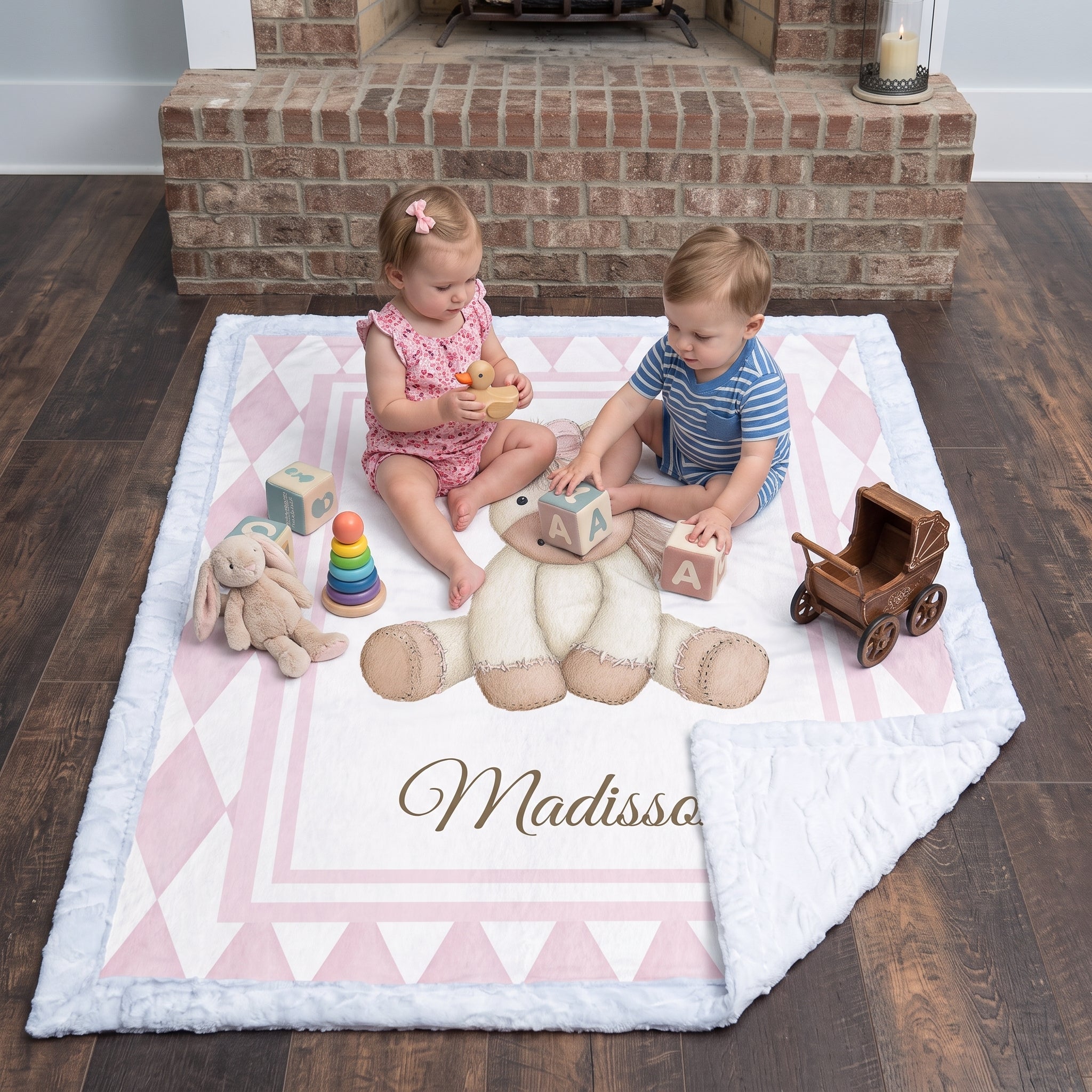 Toddlers playing with wooden toys on personalized pink pony minky blanket by fireplace