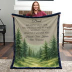 Person holding a blanket with a forest design and personalized text in a room.