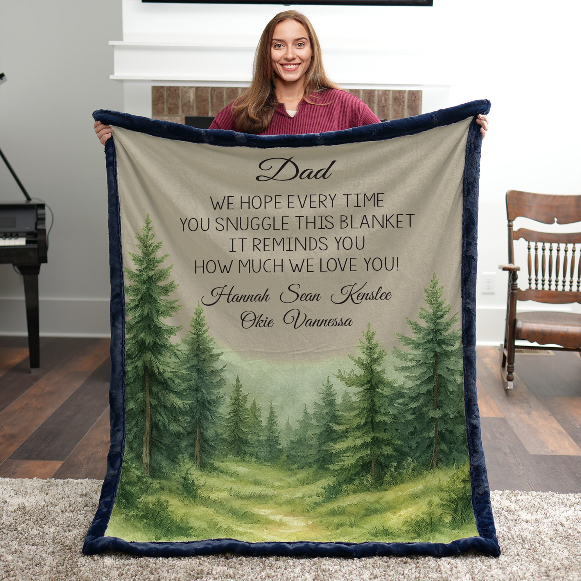 Person holding a blanket with a forest design and personalized text in a room.