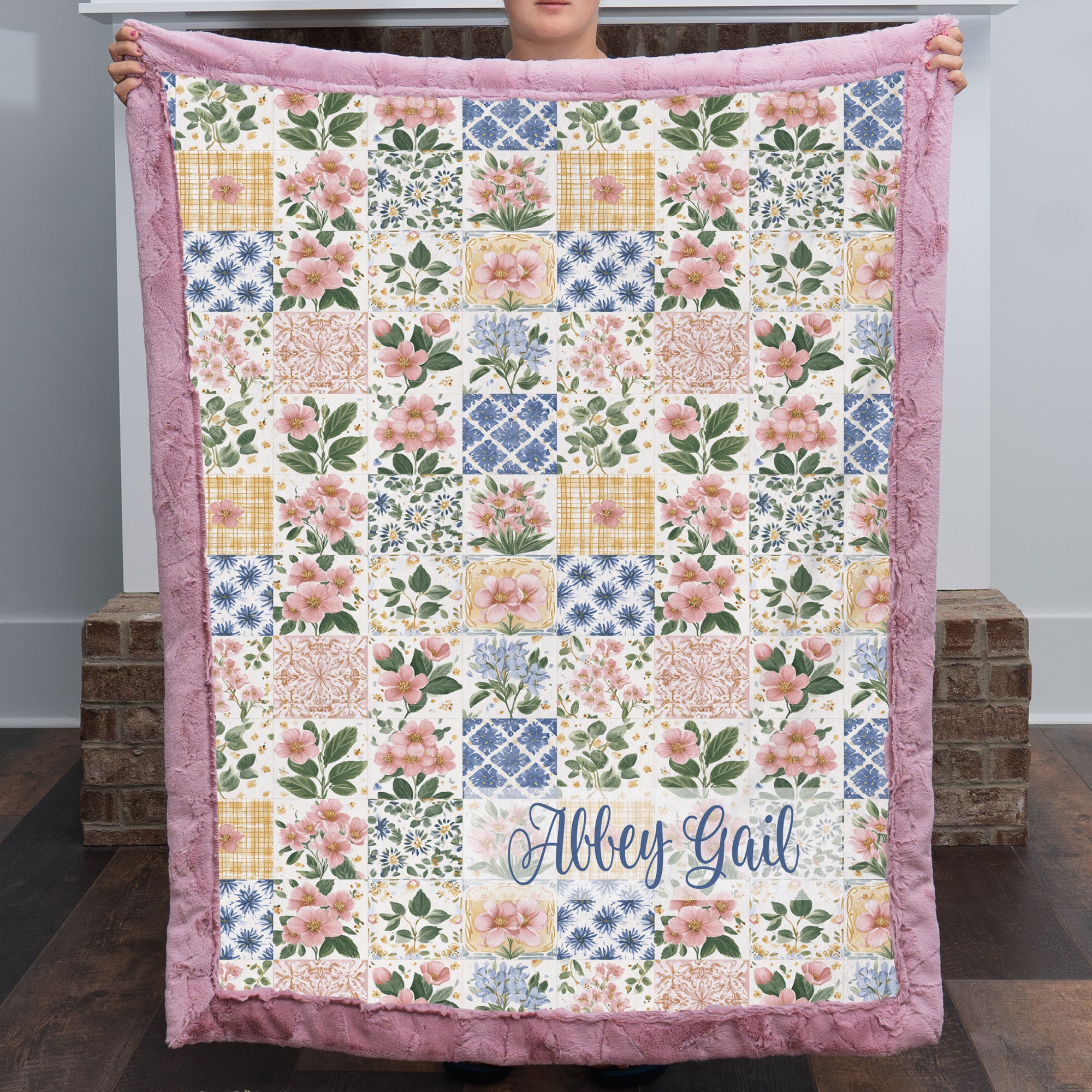 Personalized floral patchwork minky blanket folded flat showing pink trim and script name