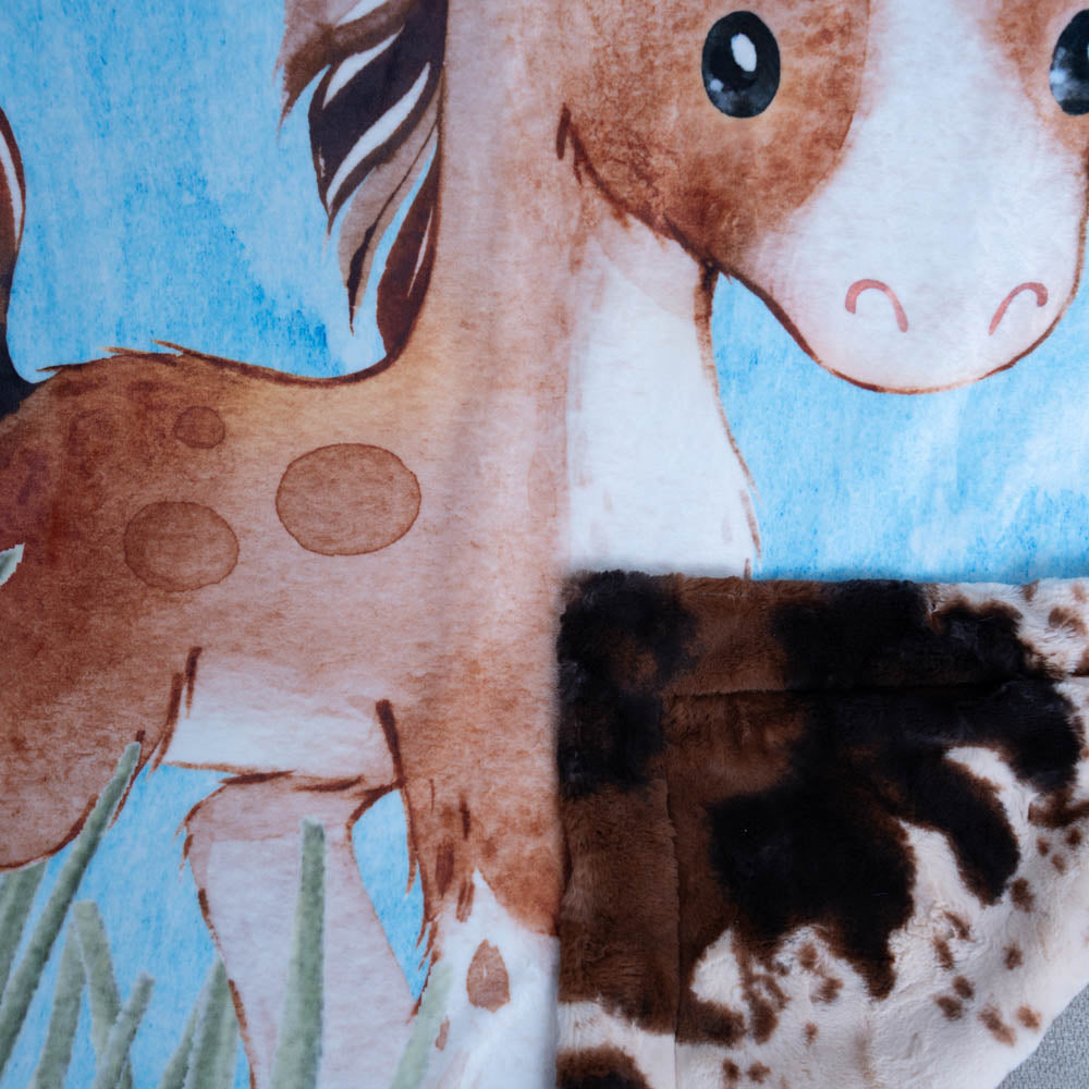 Close-up of a fabric with a horse and giraffe design on a blue background