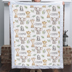 A person holds up a square quilted baby blanket featuring a safari animal print with giraffes, elephants, monkeys, and the name 'COOPER' repeated on an off-white background.