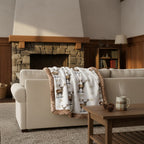 Winter elk minky blanket draped over beige sofa in living room with stone fireplace